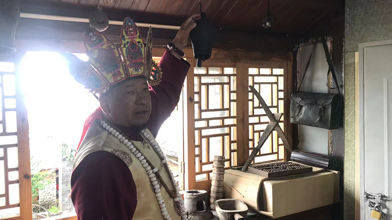 A Naxi elder is introducing his home to visitors
